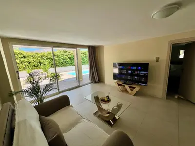 a living room with a couch and a tv at Pool Villa Lagonisi 5min from Beach in Koropíon