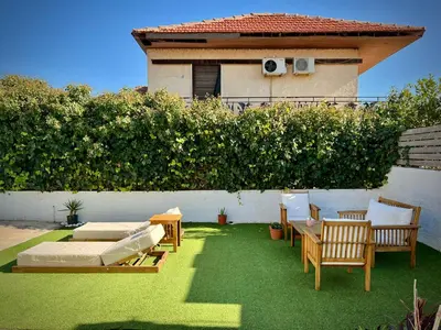 a backyard with chairs and tables and a house at Pool Villa Lagonisi 5min from Beach in Koropíon
