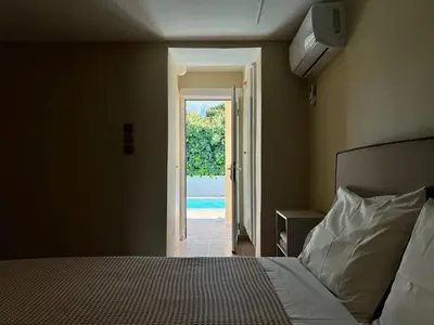 a bedroom with a bed and a door to a pool at Pool Villa Lagonisi 5min from Beach in Koropíon