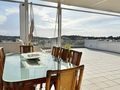 a glass dining table and chairs on a patio at Villasonboard 3 Bed Penthouse Veranda Beach view jacuzzi Vouliagmeni Riviera in Athens