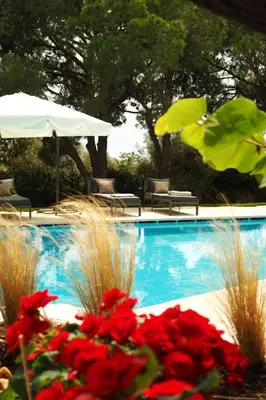 a swimming pool with red flowers in front of it at Villa Oasis with Large Pool Athenian Riviera Lagonissi in Lagonissi