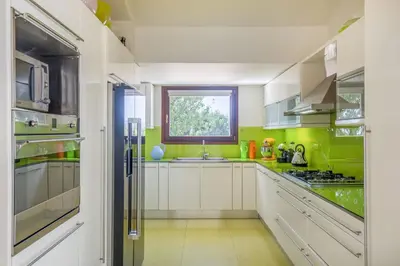 a kitchen with white cabinets and green walls at Villa Oasis with Large Pool Athenian Riviera Lagonissi in Lagonissi
