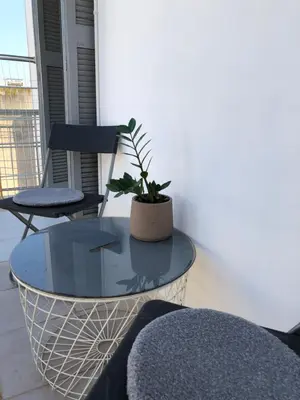 a glass table with a potted plant on a balcony at Cosy apartment in Metaxourgeio in Athens
