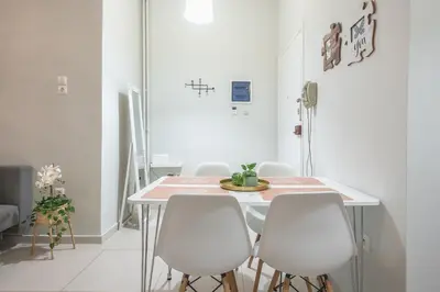 a dining room with a table and white chairs at Erythros Boutique Suite By Cloudkeys in Athens