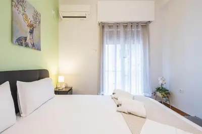 a bedroom with a large white bed and a window at Erythros Boutique Suite By Cloudkeys in Athens