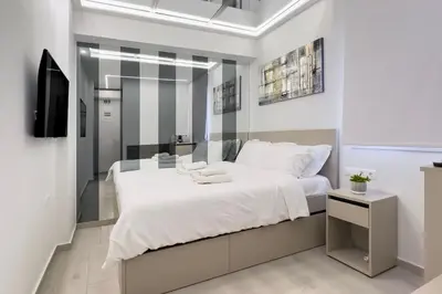a bedroom with a large white bed and a television at Stylish Living - Iro in Athens