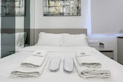a white bed with towels and slippers on it at Stylish Living - Iro in Athens