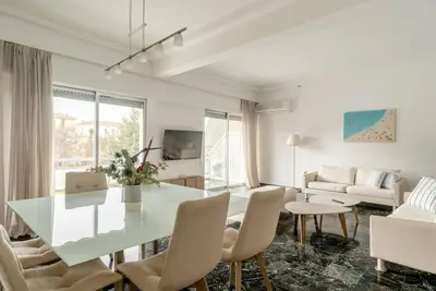 a white living room with a glass table and chairs at Elegant 2BD Evelpidon Apartment in Athens