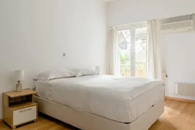 a white bedroom with a large bed and a window at Elegant 2BD Evelpidon Apartment in Athens