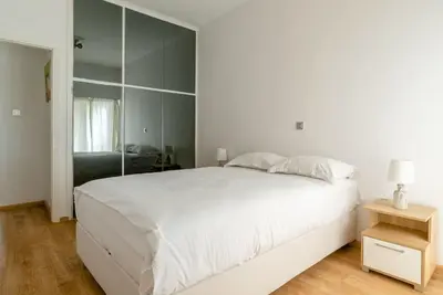 a bedroom with a large white bed and a mirror at Elegant 2BD Evelpidon Apartment in Athens