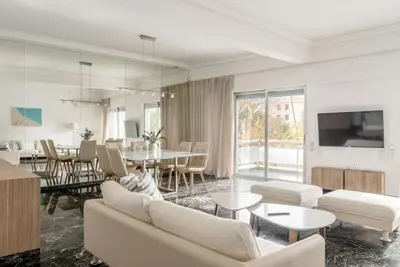 a living room with white furniture and a dining room at Elegant 2BD Evelpidon Apartment in Athens