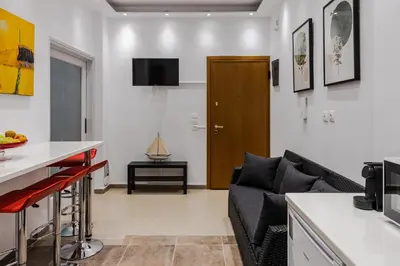a living room with a black couch and a kitchen at Bijou apartment in Glyfada center in Athens
