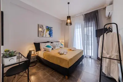 a bedroom with a bed and a table and window at Bijou apartment in Glyfada center in Athens