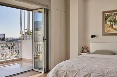 a bedroom with a bed and a glass door to a balcony at Acropolis view penthouse in Athens