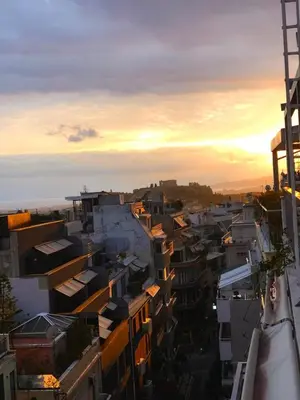 a view of a city at sunset with buildings at Acropolis view penthouse in Athens