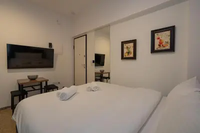 a bedroom with two white beds and a flat screen tv at Dema Luxury Suites - Lekka E3 in Athens
