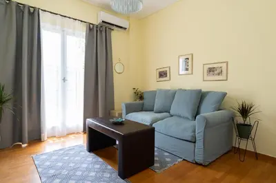 a living room with a blue couch and a table at Magnificent Bnb Athens Voula in Athens
