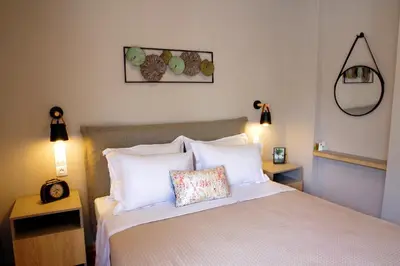 a bedroom with a bed with white pillows and a mirror at Absolute Athens XIV View in Athens