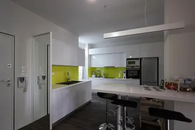 a kitchen with white cabinets and a counter with stools at Fully renovated, family-friendly apartment, next to a huge green park, in Athens center in Athens
