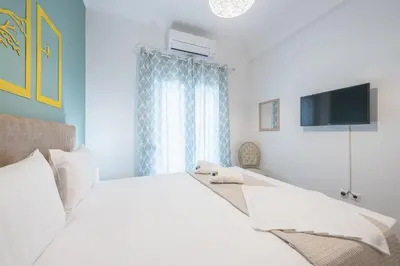 a bedroom with a white bed and a television at Easy Living Suite by Cloudkeys in Athens
