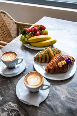 a table with two cups of coffee and a plate of fruit at Paleo Suites in Athens
