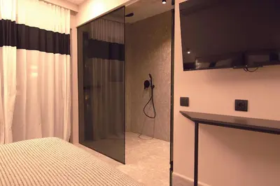 a bedroom with a shower with a glass door at Cityzoe Athens Suites in Athens