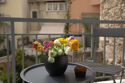 a vase of flowers sitting on a table on a balcony at Cityzoe Athens Suites in Athens