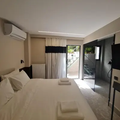 a bedroom with a large white bed and a sliding glass door at Cityzoe Athens Suites in Athens
