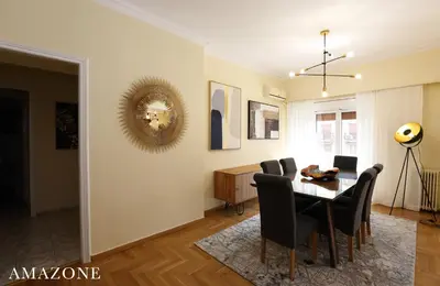 a dining room and living room with a table and chairs at MELMA PROPERTIES-AMAZONE-premium apartment in Piraeus center in Piraeus