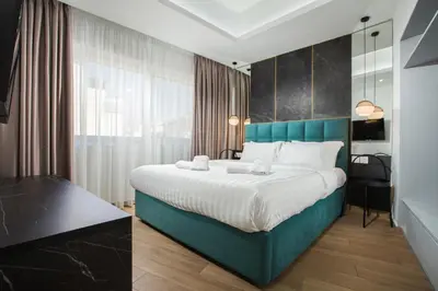a bedroom with a large bed with a blue headboard at Xclusive Athens Suites in Athens