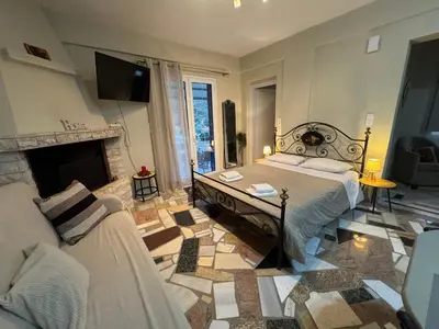 a bedroom with a bed and a couch and a fireplace at Detached House KATAFIGI in Palaiá Fókaia