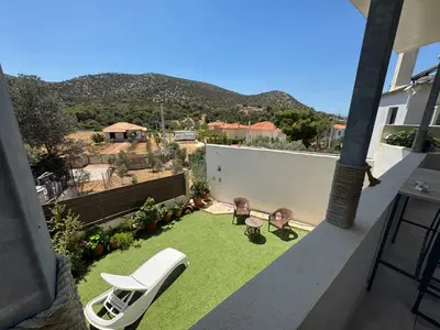 a small backyard with a lawn with a white chair at Detached House KATAFIGI in Palaiá Fókaia
