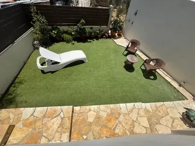 a backyard with a lawn with a white chair on it at Detached House KATAFIGI in Palaiá Fókaia