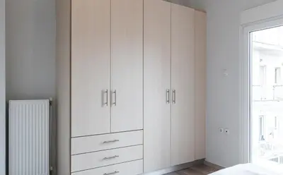 a white bedroom with white cabinets and a window at Spacious 2BD apt next to metro in Athens