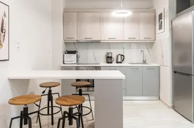 a kitchen with white cabinets and bar stools at Spacious 2BD apt next to metro in Athens