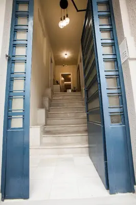 a hallway with blue doors and stairs in a building at Lovely 1st Fl. Apt, with Balcony in Pagrati in Athens