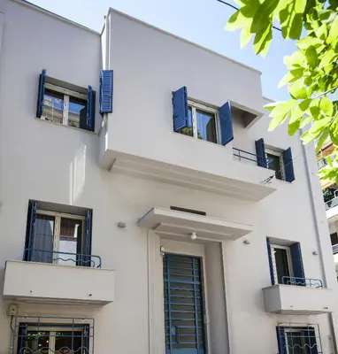 a white building with blue shuttered windows at Lovely 1st Fl. Apt, with Balcony in Pagrati in Athens