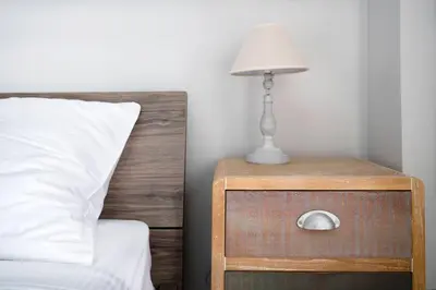 a nightstand with a lamp on it next to a bed at The 