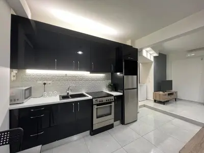 a kitchen with black cabinets and a stainless steel refrigerator at Thiseio Residence- Studio 55 in Athens
