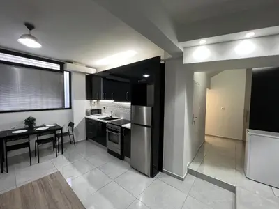 a kitchen with black cabinets and a table and a dining room at Thiseio Residence- Studio 55 in Athens