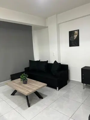 a living room with a black couch and a coffee table at Thiseio Residence- Studio 55 in Athens