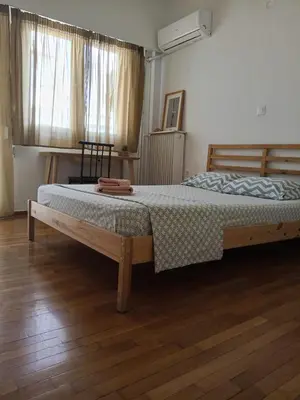a large bed in a bedroom with a wooden floor at Cicada 's Song in Athens