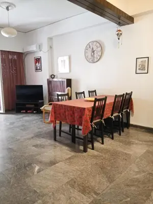 a dining room table with chairs and a clock on the wall at Cicada 's Song in Athens