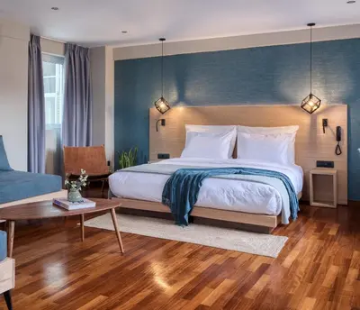 a bedroom with a large bed with a blue wall at Arcade Hotel Athens in Athens