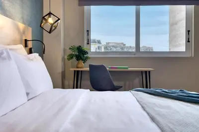 a bedroom with a bed and a desk and a window at Arcade Hotel Athens in Athens