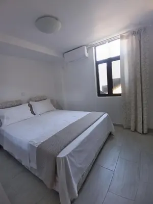 a white bedroom with a bed and a window at ΟΔΥΣΣΕΙΑ, κοντά σε αεροδρόμιο, λιμάνια και θάλασσες in Keratea