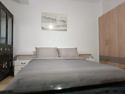 a bedroom with a large bed and a wooden cabinet at ΟΔΥΣΣΕΙΑ, κοντά σε αεροδρόμιο, λιμάνια και θάλασσες in Keratea