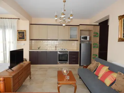a living room with a couch and a kitchen at ΟΔΥΣΣΕΙΑ, κοντά σε αεροδρόμιο, λιμάνια και θάλασσες in Keratea