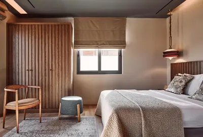 a bedroom with a bed and a chair and a window at Cama Luxury Suites Glyfada in Athens