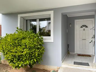 a house with a white door and a green bush at Kalimera Alimos Apartment in Athens
